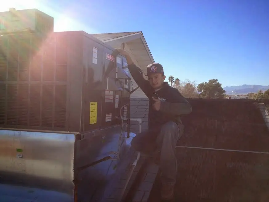 HVAC technician performing AC Tune-Up on a rooftop unit in Brick
